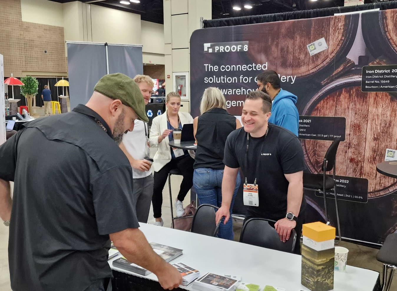 Proof 8 team at a trade show with Digital Deeds on the booth backdrop